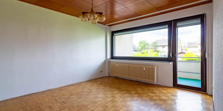 Das Wohnzimmer mit Parkettboden und Zugang zum Balkon lädt zum Wohlfühlen ein